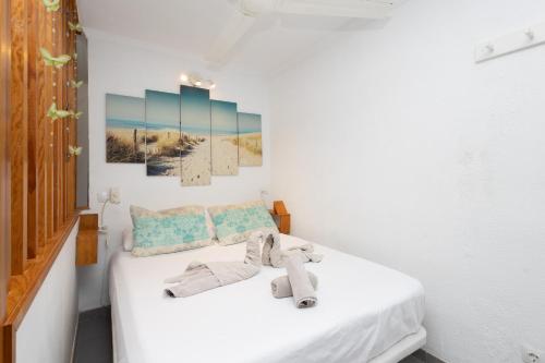 een slaapkamer met een bed met witte lakens bij Lightbooking Don Paco Patalavaca in Mogán
