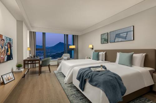 a large bedroom with a large bed and a desk at Citadines Qingshanhu Hangzhou in Hangzhou
