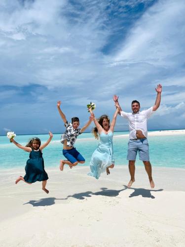a group of people jumping on the beach at Three Hearts Guesthouse and Villas in Fulhadhoo