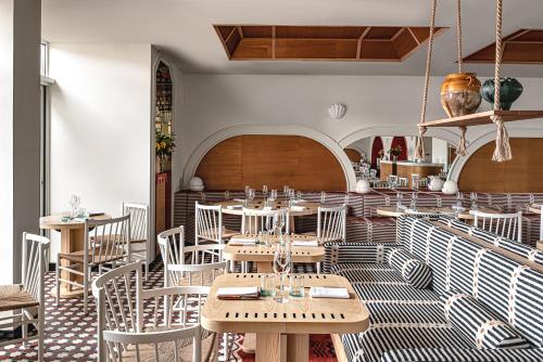 Regina Experimental Biarritz في بياريتز: مطعم بطاولات خشبية وكراسي بيضاء