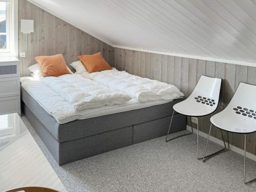 a bed in a room with two white chairs at Holiday home HOVDEN II in Hovden