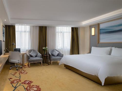 1 dormitorio con 1 cama blanca grande y 2 sillas en Vienna Classic Hotel Shenzhen Pingshan Bihu Hotel, en Longgang