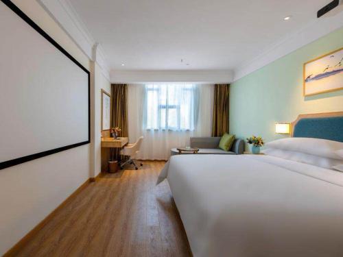 ein Hotelzimmer mit einem großen weißen Bett und einem Sofa in der Unterkunft Vienna SanHao Hotel Danyang Houxiang in Matunlijia