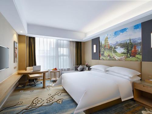 Schlafzimmer mit einem großen weißen Bett und einem Schreibtisch in der Unterkunft Vienna International Hotel Jurong Huayang in Jurong