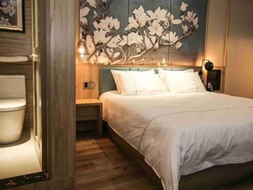 a bedroom with a bed and a painting on the wall at Magnolia Business Hotel Yangzhou Wanda Plaza Shunda Road in Yangzhou