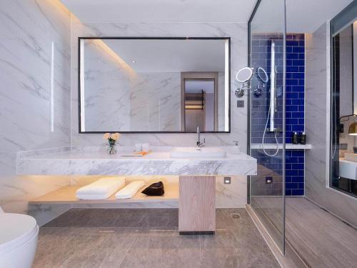 a bathroom with a sink and a mirror at Kyriad Marvelous Hotel Hezhou Wanda Plaza in Hezhou