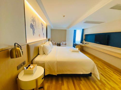 una habitación de hotel con una gran cama blanca y una mesa en Kyriad Marvelous Hotel Shantou Railway Station, en Shantou