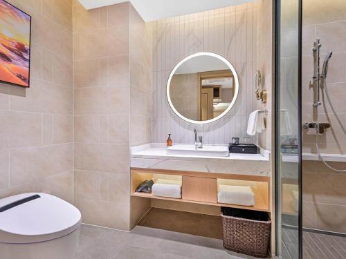 a bathroom with a sink and a toilet and a mirror at Vienna International Hotel Chongqing Central Park 5 0 in Chongqing