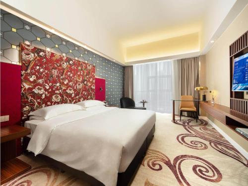 a hotel room with a large bed and a tv at Metropolo Hotel Zhenjia Wanda Plaza Railway Station in Zhenjiang