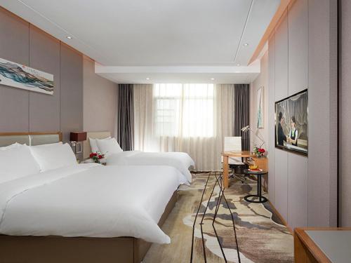 LongnanにあるVienna International Hotel Ganzhou Longnanのベッド2台と窓が備わるホテルルームです。