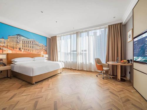 een hotelkamer met een groot bed en een bureau bij Vienna Hotel Jiangyin Zhouzhuang in Jiangyin
