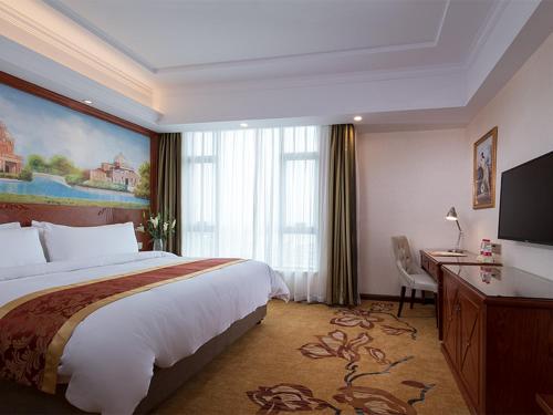 a hotel room with a large bed and a desk at Vienna Hotel Jieyang Rongjiangxincheng Store in Jieyang