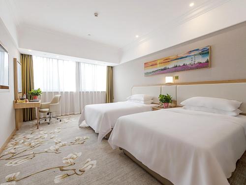 a hotel room with two beds and a desk at Vienna SanHao Hotel Jiangsu Danyang Jinying in Danyang