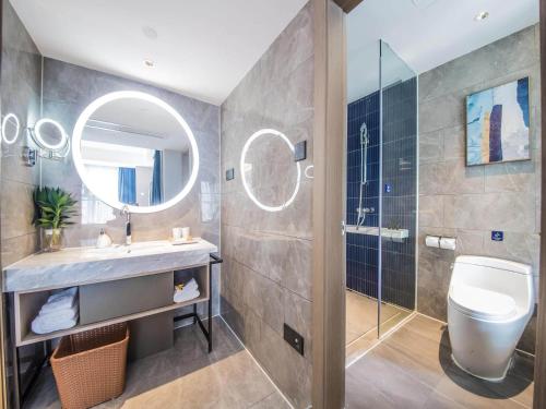 a bathroom with a sink and a toilet and a mirror at Kyriad Marvelous Hotel Qinhuangdao Nandaihe in Qinhuangdao