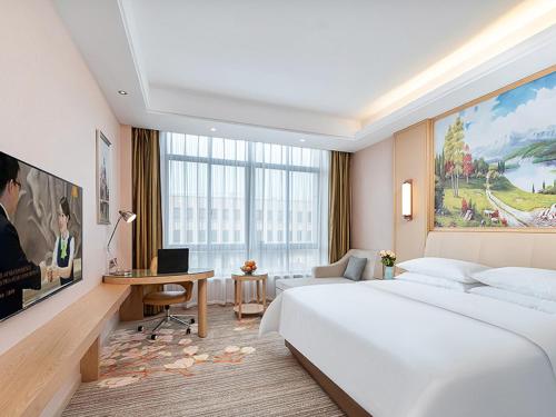 um quarto com uma grande cama branca e uma secretária em Vienna Hotel Danyang Glasses City High Speed Railway Station Dabo em Danyang