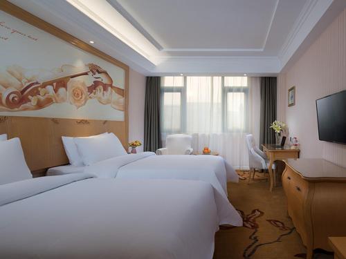 Vienna Hotel Huaidong Road Yuncheng في يونتشنغ: غرفة فندقية بسريرين وتلفزيون بشاشة مسطحة