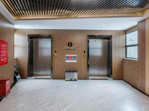 an empty lobby with two elevators in a building at Kyriad Marvelous Hotel Shenzhen North Railway Station Yousong in Tiantangwei