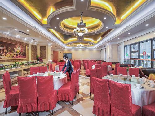 una sala da pranzo con tavoli e sedie rosse e una donna di Vienna International Hotel Wuxi Huishan Yanqiao Metro Station a Wuxi
