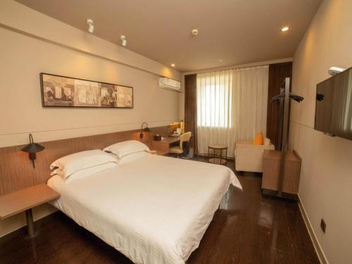 a bedroom with a large white bed and a desk at Jinjiang Inn Select Yangzhou Slender West Lake Siwangting Road in Yangzhou