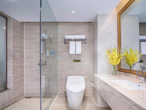 a bathroom with a shower and a toilet and a sink at Vienna International Hotel Mongolia Chifeng High-Speed Railway Station in Chifeng