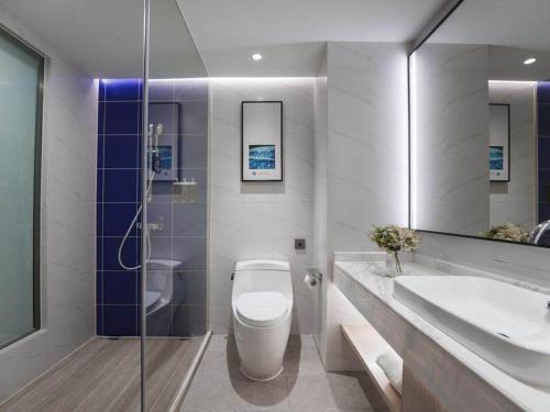 a bathroom with a toilet and a sink and a mirror at Kyriad Marvelous Hotel Shenzhen Guangming Zhenmei Subway Station in Bao'an