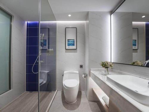 La salle de bains est pourvue de toilettes, d'un lavabo et d'un miroir. dans l'établissement Kyriad Marvelous Hotel Shenzhen Guangming Zhenmei Subway Station, à Bao'an