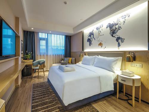 a hotel room with a large white bed and a television at Kyriad Marvelous Hotel Suzhou Guanqian Street and Shiquan Street in Suzhou