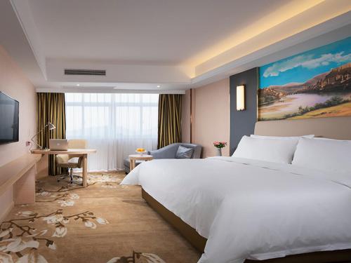 um quarto com uma grande cama branca e uma secretária em Vienna Hotel Yichun Administration Center store em Yichun