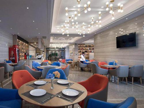 un restaurante con mesas, sillas y TV en Kyriad Marvelous Hotel Foshan Nanzhuang Taobo Avenue, en Foshan