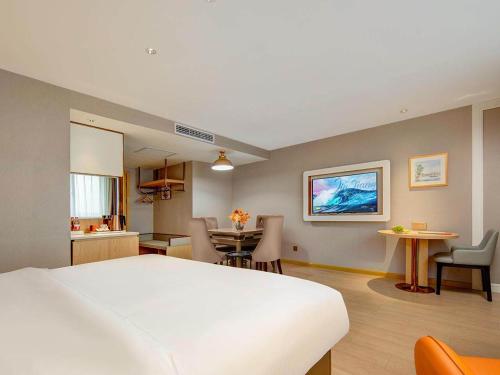 a bedroom with a large white bed and a kitchen at Vienna Hote Nanjing Lishui Tianshengqiao Avenue Wuxiang Shuizhen 5 0 in Lishui