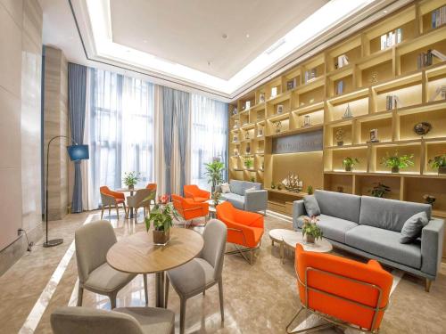 a waiting room with couches and tables and chairs at Kyriad Marvelous Hotel Qinhuangdao Nandaihe in Qinhuangdao