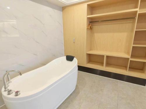 eine weiße Badewanne im Badezimmer mit Regalen in der Unterkunft Kailyad Hotel Jiujiang Duchang Pedestrian Street in Duchang