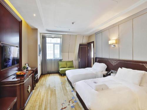 a hotel room with two beds and a television at Kyriad Marvelous Hotel Harbin Railway Station Central Avenue in Harbin