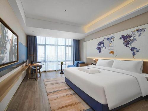 um quarto com uma grande cama branca e um mapa do mundo na parede em Kyriad Hotel Dongguan Houjie Convention and Exhibition Center Humen Station em Dongguan