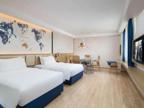a hotel room with two beds and a table at Kyriad Hotel Shenzhen Pingdi Low Carbon City in Longgang