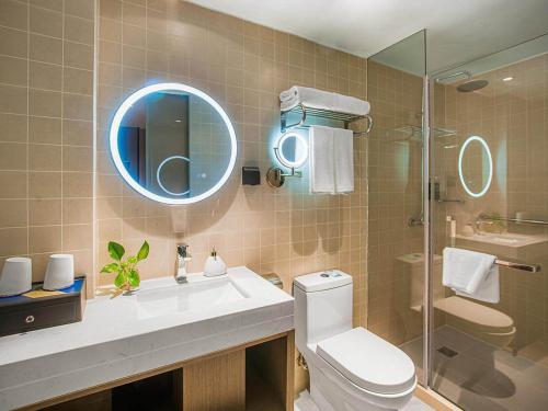 a bathroom with a sink and a toilet and a mirror at Kyriad Marvelous Hotel Wuxi Zhongshan Road Chong'an Temple in Wuxi