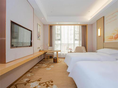 Habitación de hotel con 2 camas, escritorio y TV. en Vienna International Hotel Nanchang Qingshan Lake Wanda Plaza, en Nanchang