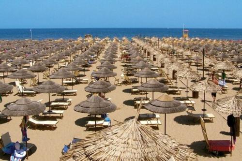 a large group of umbrellas and chairs on a beach at Appartamento AmaRèmin - Vivere Rimini in Rimini