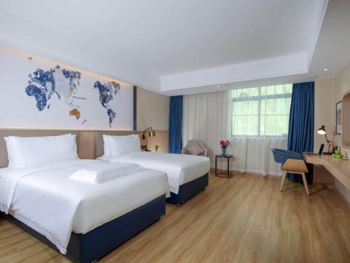 a hotel room with two beds and a desk at Kyriad Marvelous Hotel Zhongshan West District in Changzhou