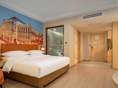 a bedroom with a large bed with a painting on the wall at Vienna Hote Nanjing Lishui Tianshengqiao Avenue Wuxiang Shuizhen 5 0 in Lishui