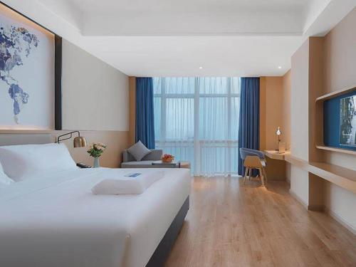 a hotel room with a large bed and a television at Kyriad Marvelous Hotel Huizhou Boluo Longxi in Boluo