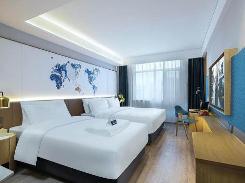a hotel room with two white beds and a desk at Kyriad Marvelous Hotel Weihai Happy Gate Weigao Plaza in Weihai