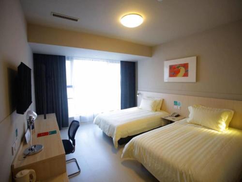 a hotel room with two beds and a window at Jinjiang Inn Yangzhou Gaoyou East Haichao Road in Gaoyou