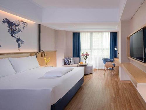 ein Hotelzimmer mit einem großen Bett und einem TV in der Unterkunft Kyriad Marvelous Hotel Haikou Free Trade Zone in Haikou