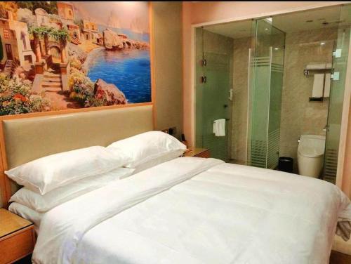 Un dormitorio con una gran cama blanca y una pintura en Vienna International Hotel Zhejiang Wenzhou Ruian Tangxia, en Ruian