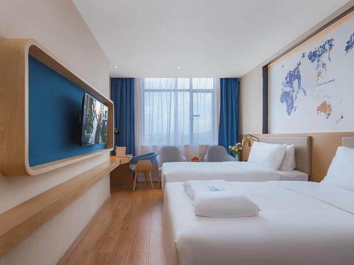 um quarto de hotel com duas camas e uma televisão de ecrã plano em Kyriad Marvelous Hotel Huizhou Boluo Longxi em Boluo