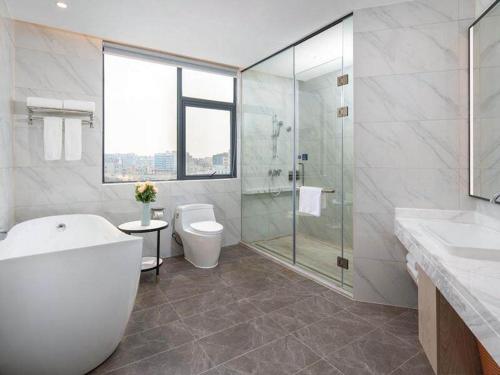 a bathroom with a tub and a toilet and a shower at Kyriad Marvelous Hotel Shenzhen Baoan Gushu Metro Station in Bao'an