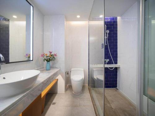 a bathroom with a sink and a toilet and a shower at Kyriad Marvelous Hotel Yiyang Ziyang in Yiyang