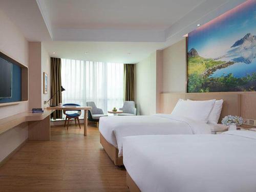 Habitación de hotel con 2 camas, escritorio y TV. en Kyriad Marvelous Hotel Dongguan Huangjiang Jingyi en Dongguan