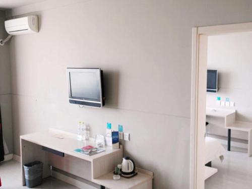 a bathroom with a sink and a tv on the wall at Jinjiang Inn Jurong Renmin Road Gexianhu Park in Jurong